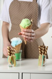 Woman holding waffle cone with cotton candy indoors, closeup