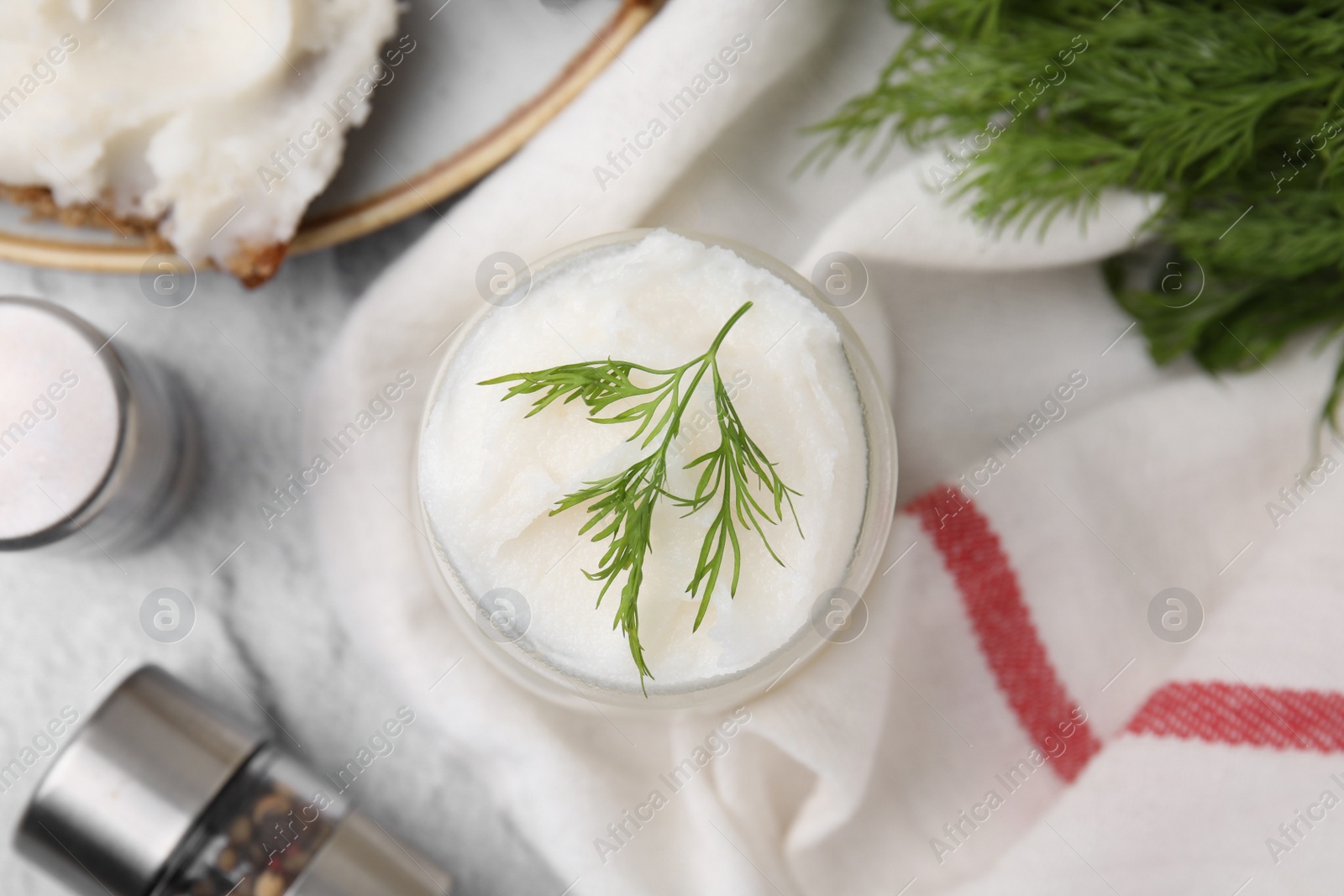 Photo of Delicious pork lard with dill in glass jar and spice shakers on light textured table, flat lay