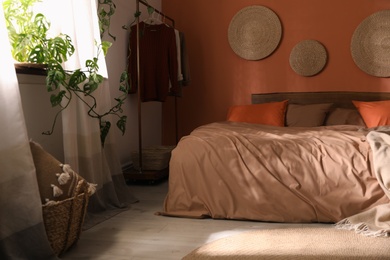 Bed with orange and brown linens in stylish room interior