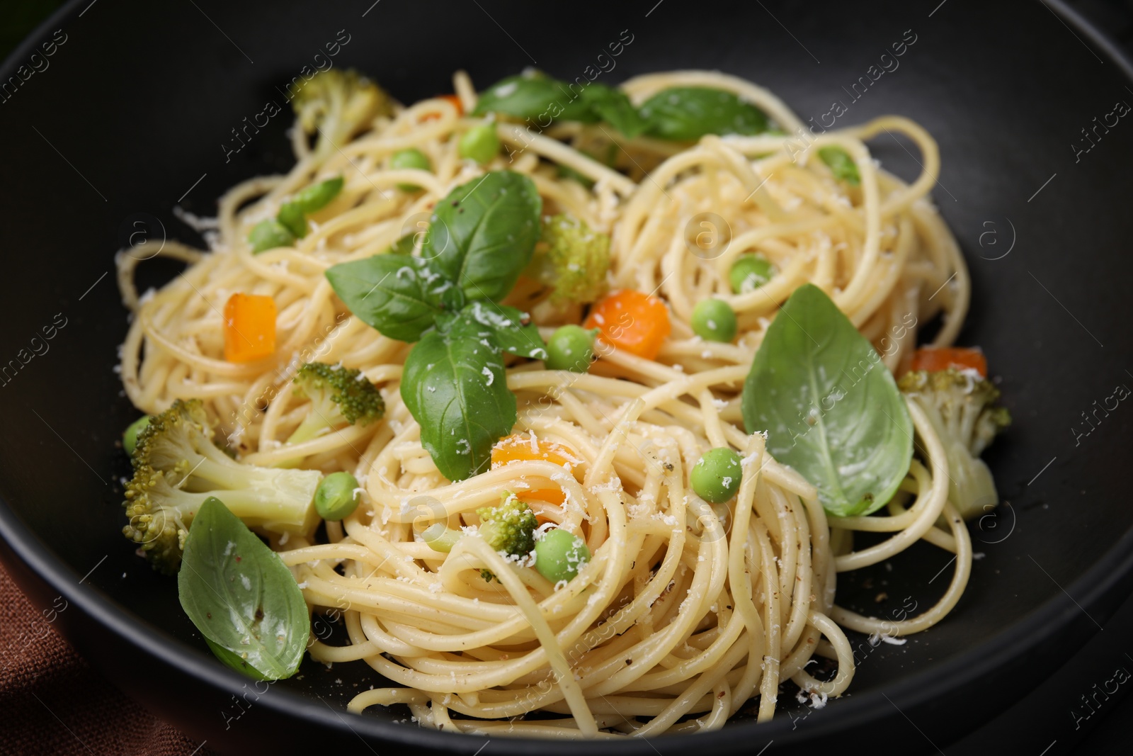 Photo of Delicious pasta primavera with basil, broccoli and peas in bowl, closeup