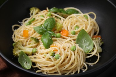 Delicious pasta primavera with basil, broccoli and peas in bowl, closeup