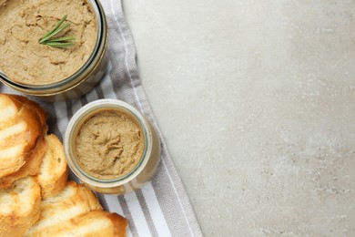 Glass jars with tasty liver pate and bread on light grey table, top view. Space for text