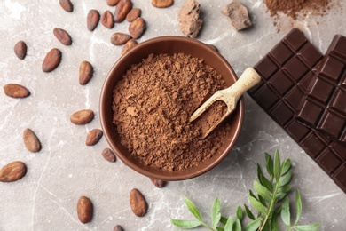 Flat lay composition with cocoa powder, beans and chocolate on light background