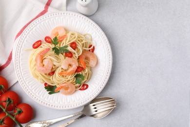 Photo of Tasty spaghetti with shrimps, chili pepper and parsley served on grey table, flat lay. Space for text