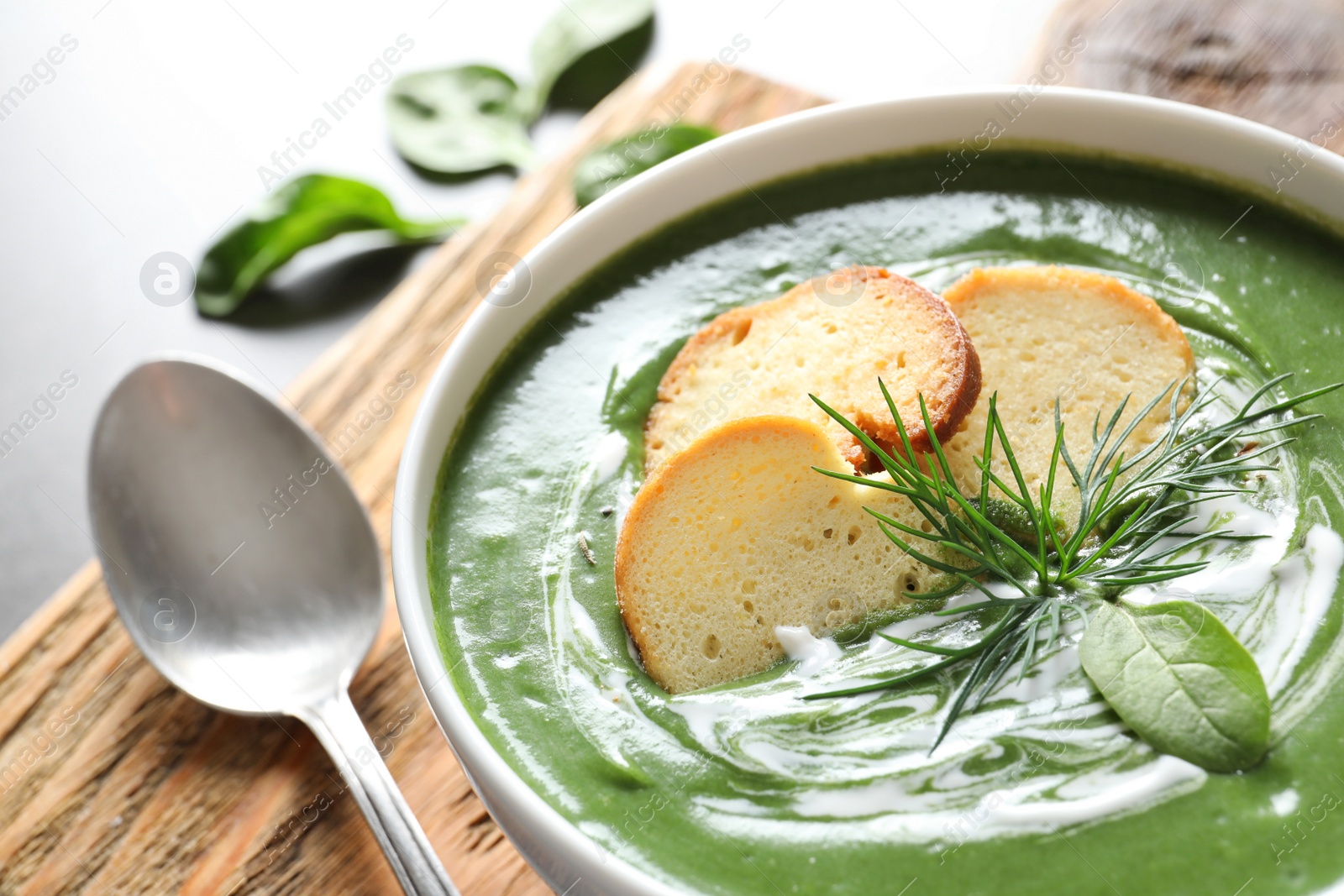 Photo of Fresh vegetable detox soup made of spinach with croutons in dish served on table, closeup