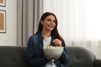 Photo of Happy woman with bowlpopcorn watching TV at home