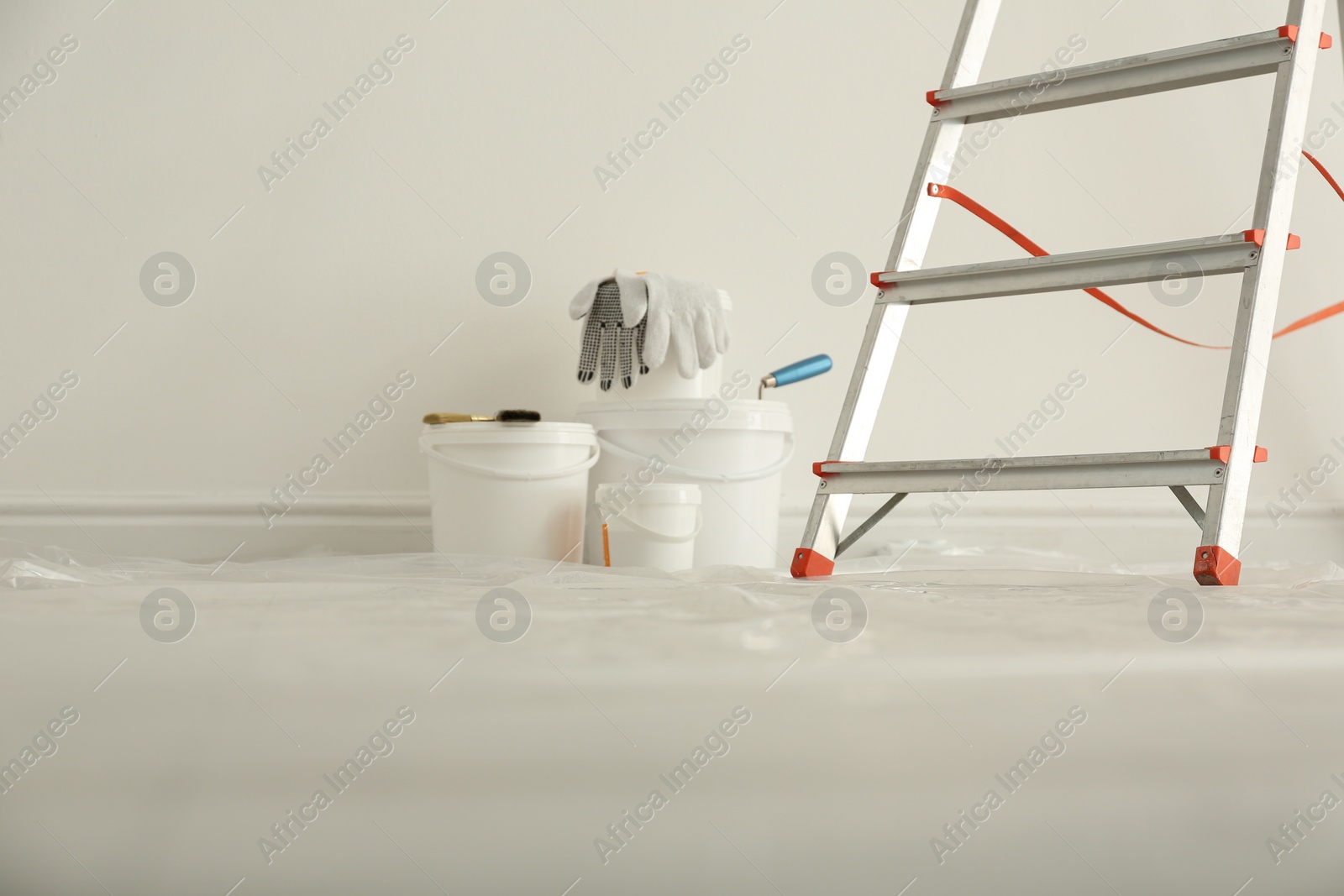 Photo of Stepladder and different tools near wall in room. Interior renovation