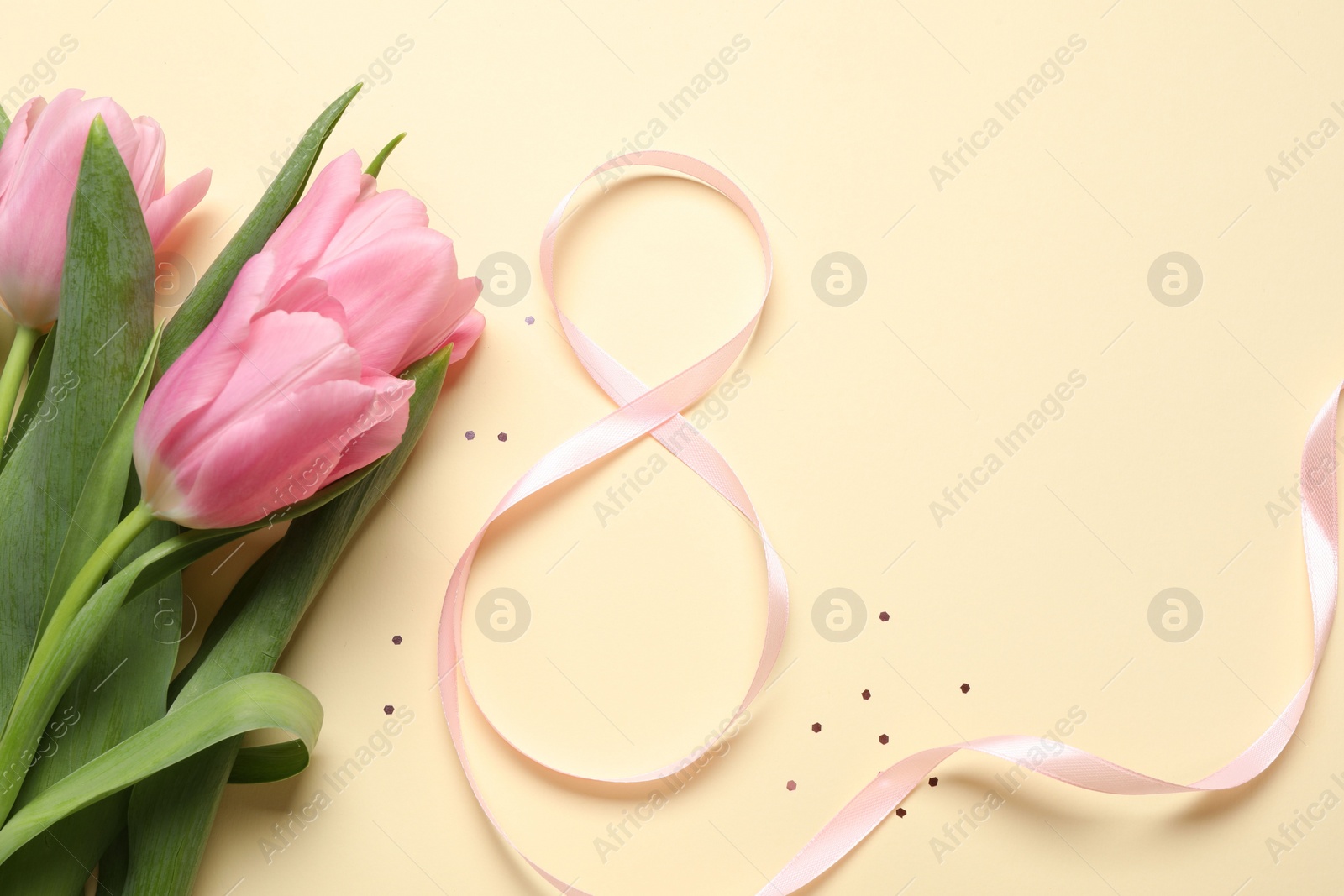 Photo of 8th of March greeting card design with pink ribbon, beautiful flowers and space for text on beige background, flat lay. International Women's day