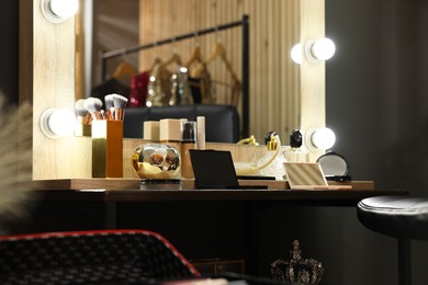 Photo of Makeup brushes and cosmetic products on dressing table in room