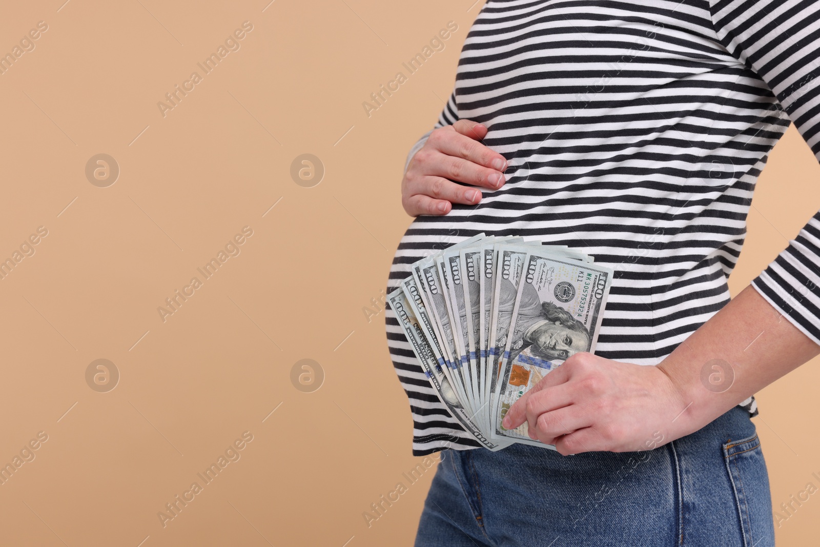 Photo of Surrogate mother. Pregnant woman with dollar banknotes on beige background, closeup. Space for text