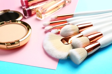 Professional makeup brushes and different decorative cosmetics on color background