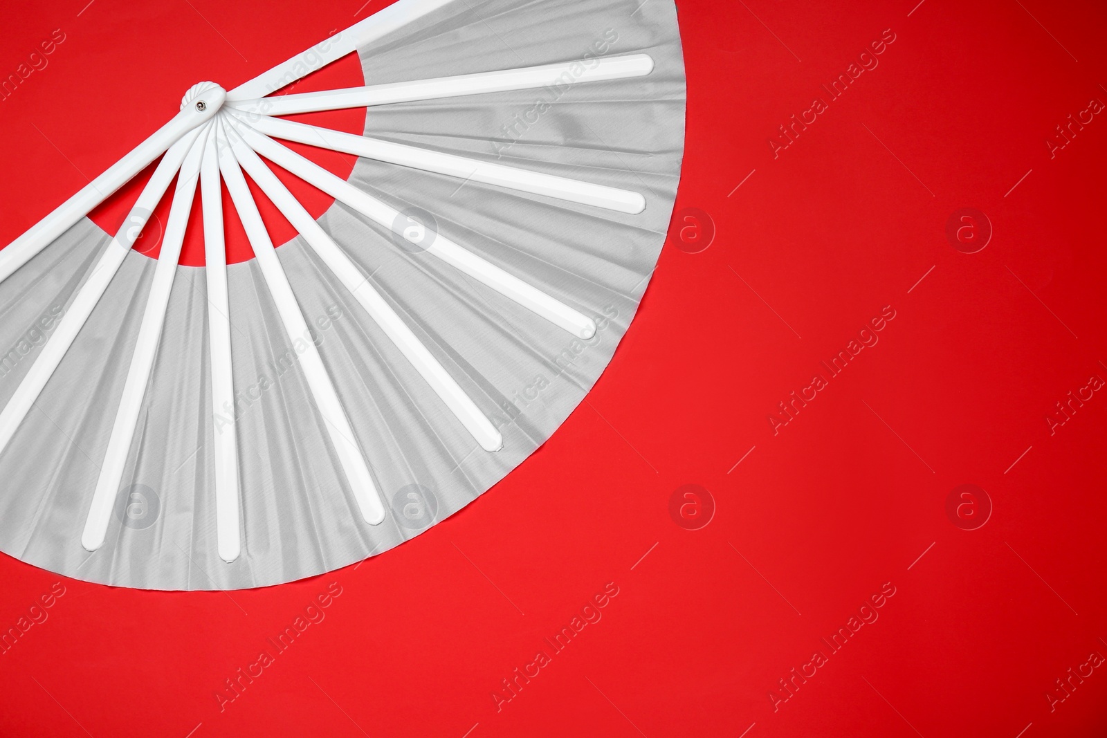 Photo of Stylish white hand fan on red background, top view. Space for text