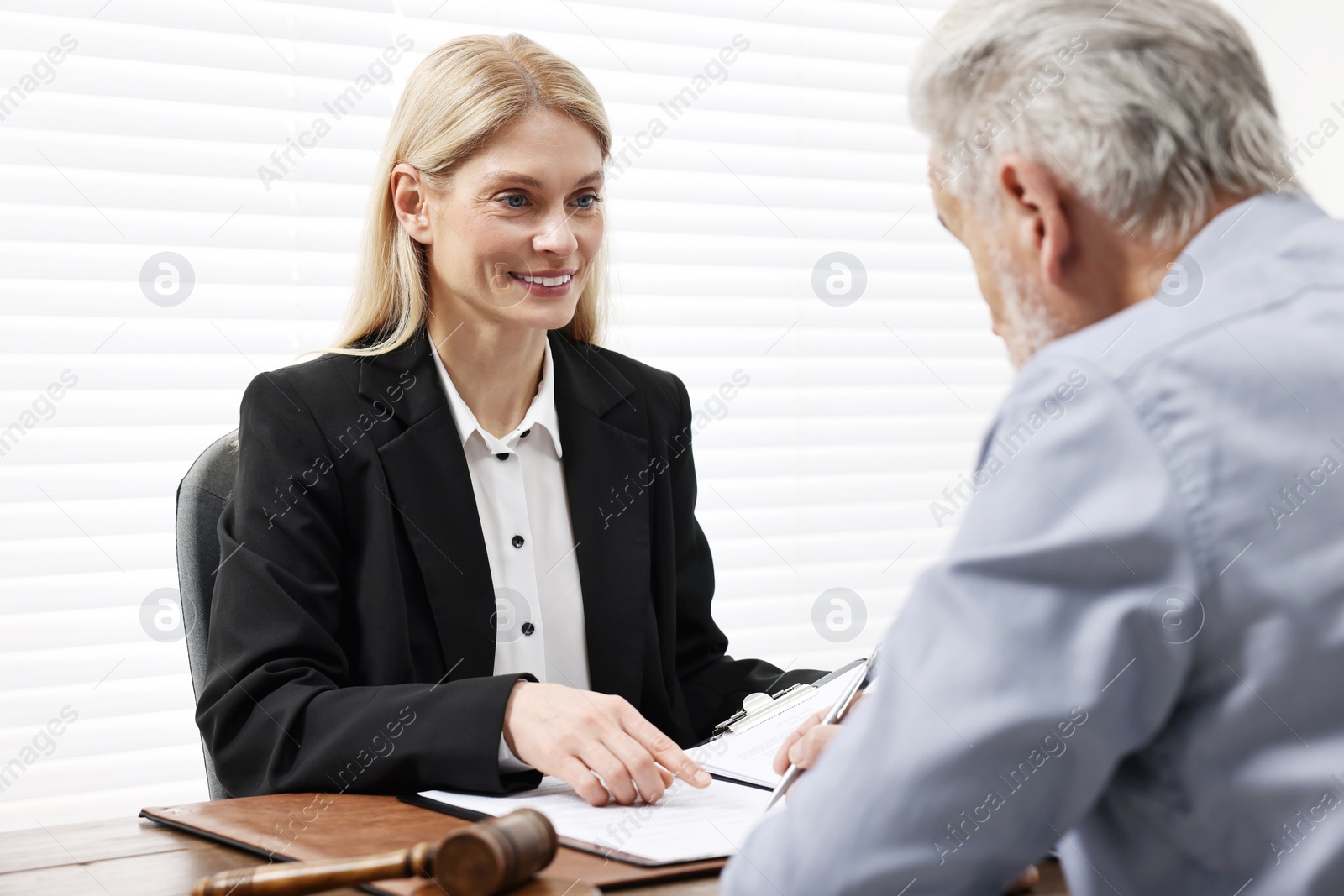 Photo of Senior man signing document in lawyer's office