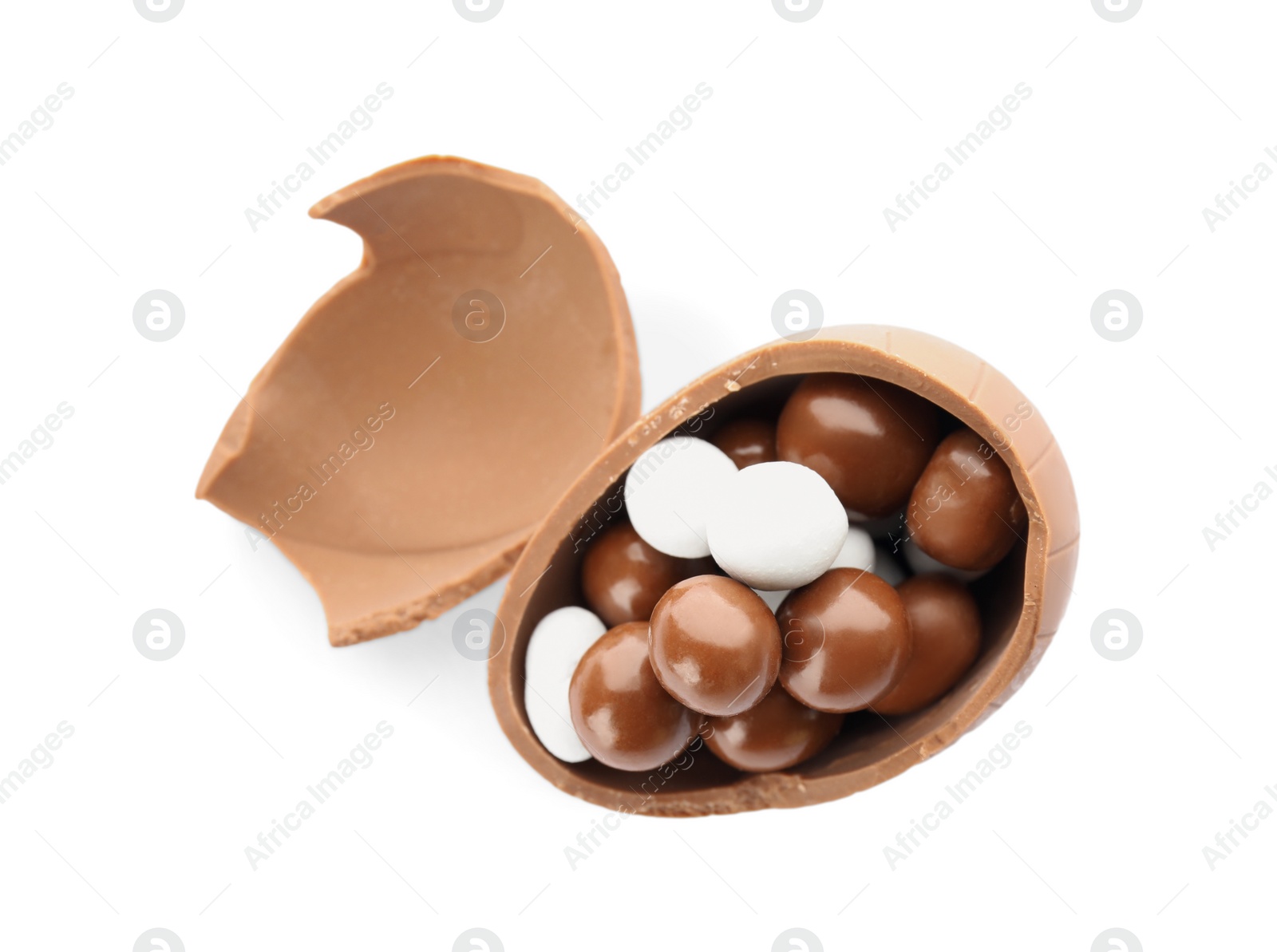 Photo of Broken chocolate egg with candies on white background, top view