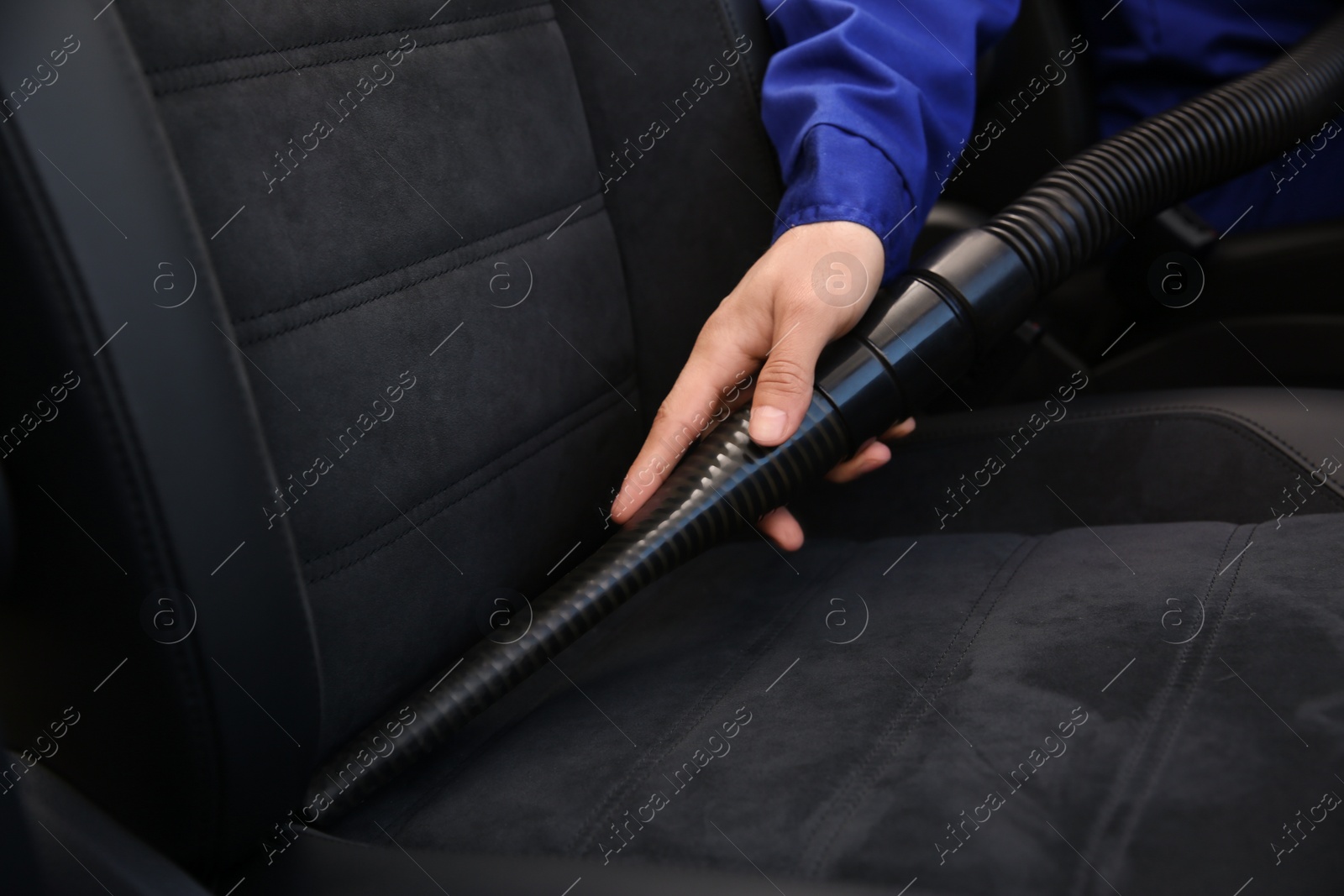 Photo of Car wash worker vacuuming automobile seat, closeup