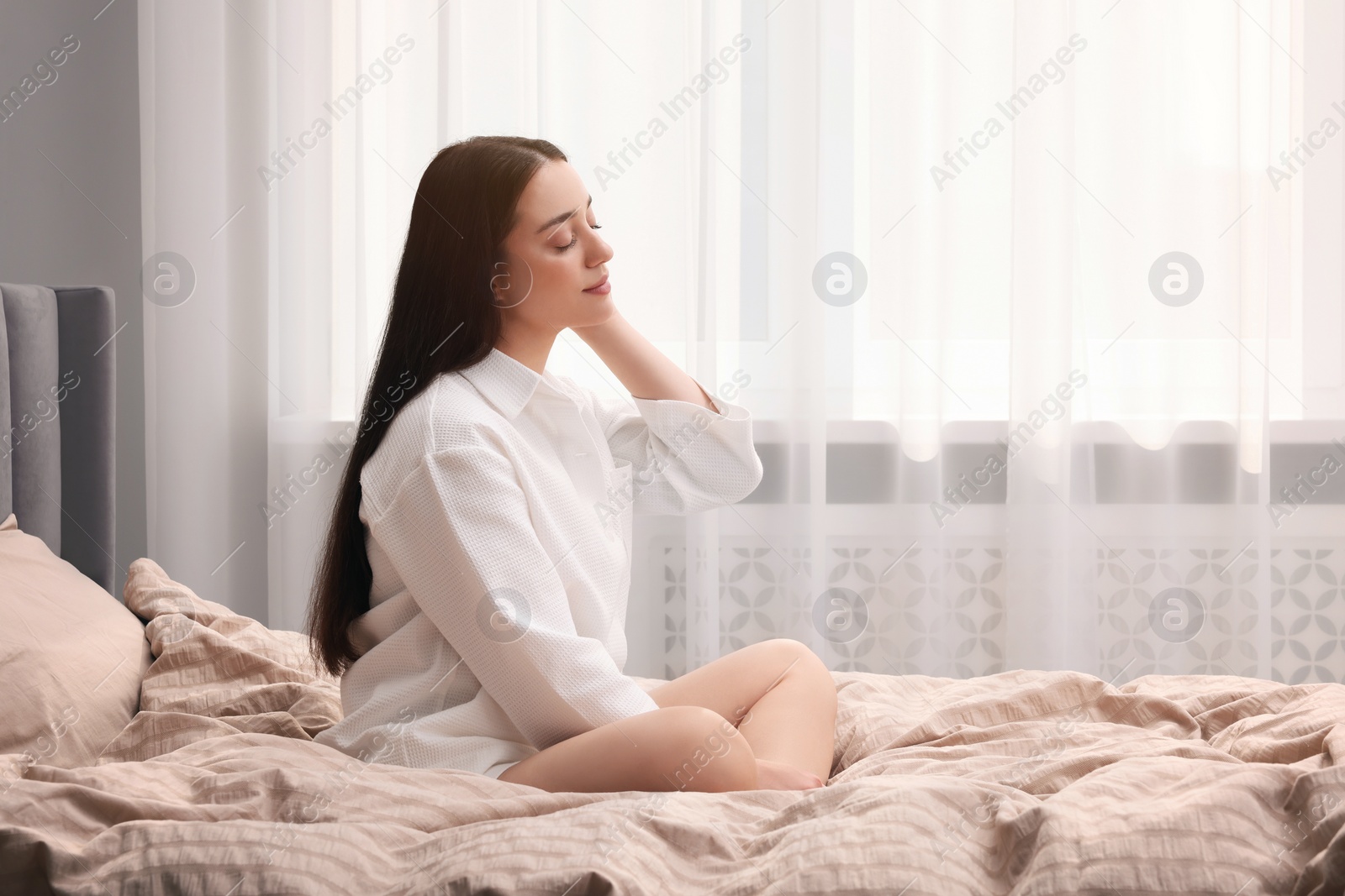 Photo of Beautiful woman sitting on bed at home, space for text. Lazy morning