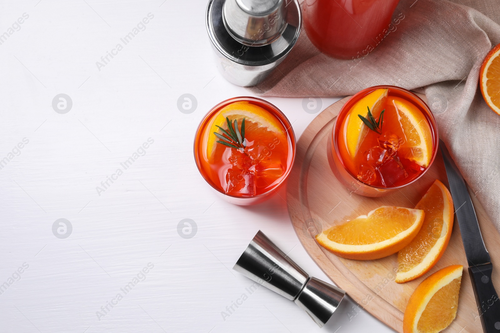 Photo of Aperol spritz cocktail, rosemary and orange slices in glasses on white wooden table, flat lay. Space for text