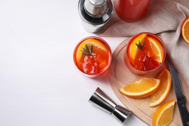Photo of Aperol spritz cocktail, rosemary and orange slices in glasses on white wooden table, flat lay. Space for text