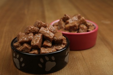 Photo of Wet pet food in feeding bowls on wooden background