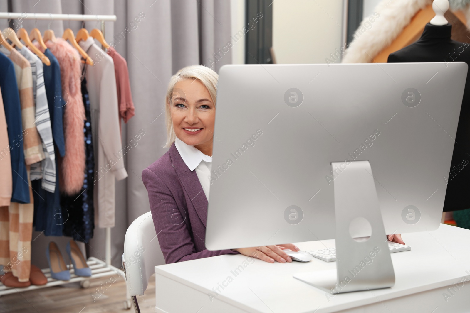 Photo of Female business owner working with computer in boutique