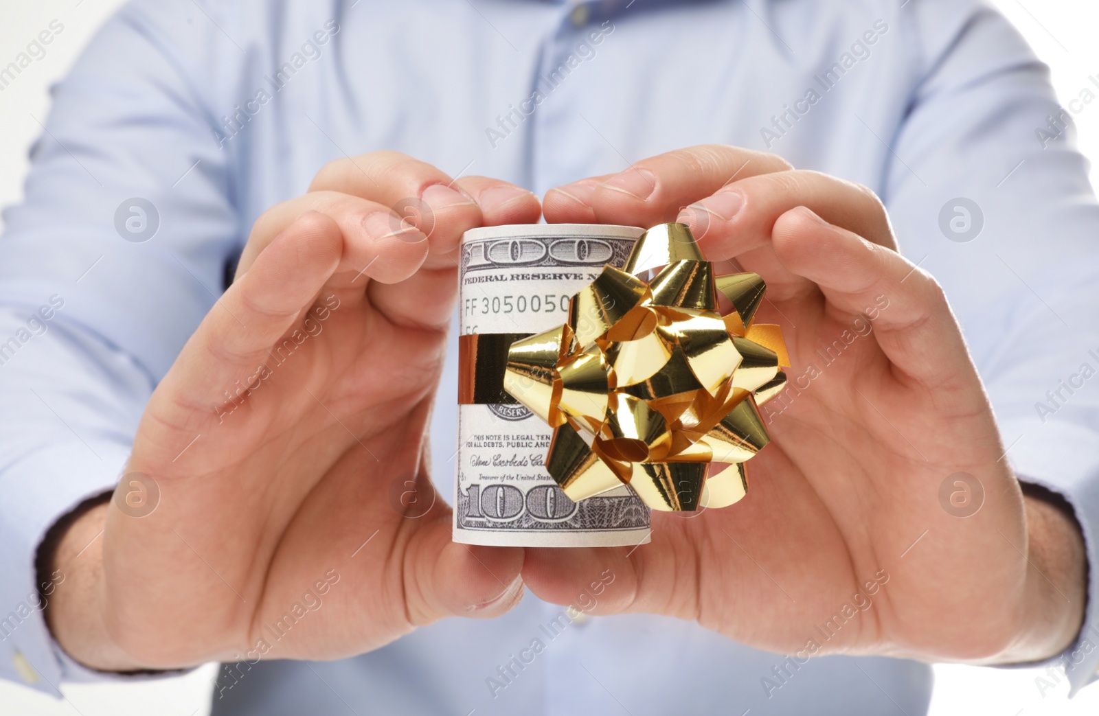 Photo of Man holding roll of dollar bills with bow on white background, closeup