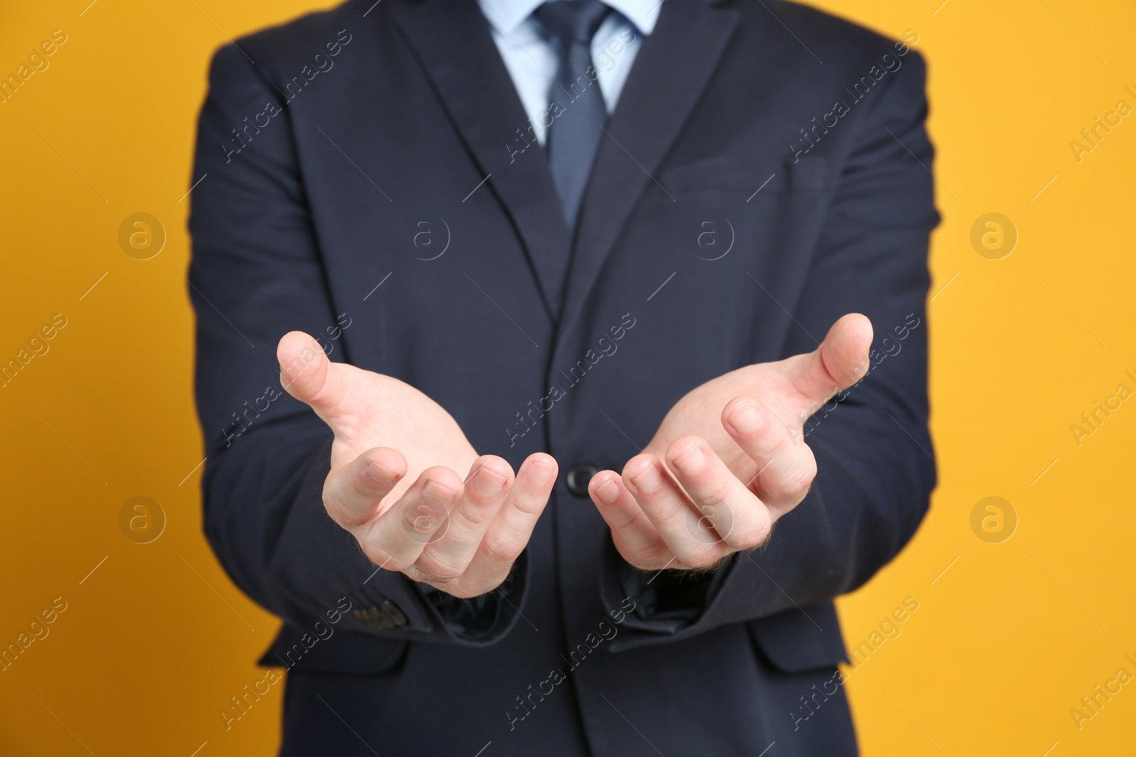 Photo of Businessman holding something against orange background, focus on hands