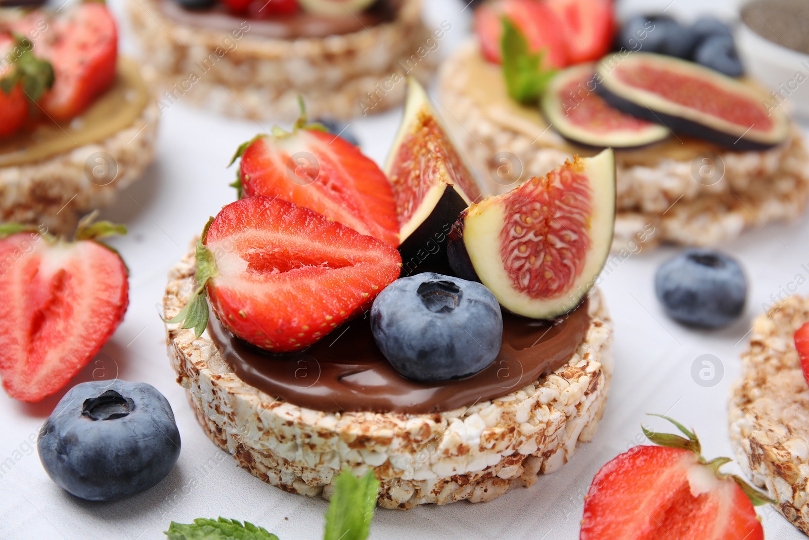 Photo of Tasty crispbreads with chocolate, figs and berries on light table, closeup