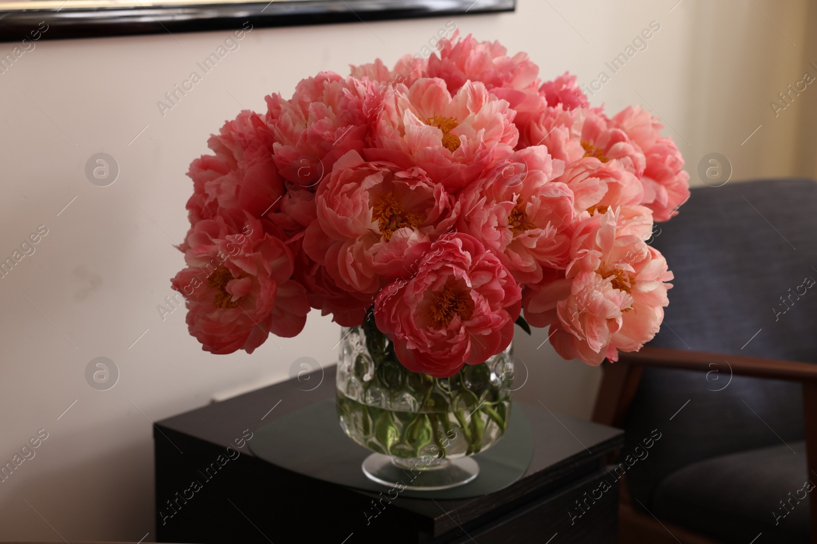 Photo of Beautiful pink peonies in vase on nightstand indoors