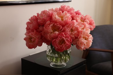 Beautiful pink peonies in vase on nightstand indoors