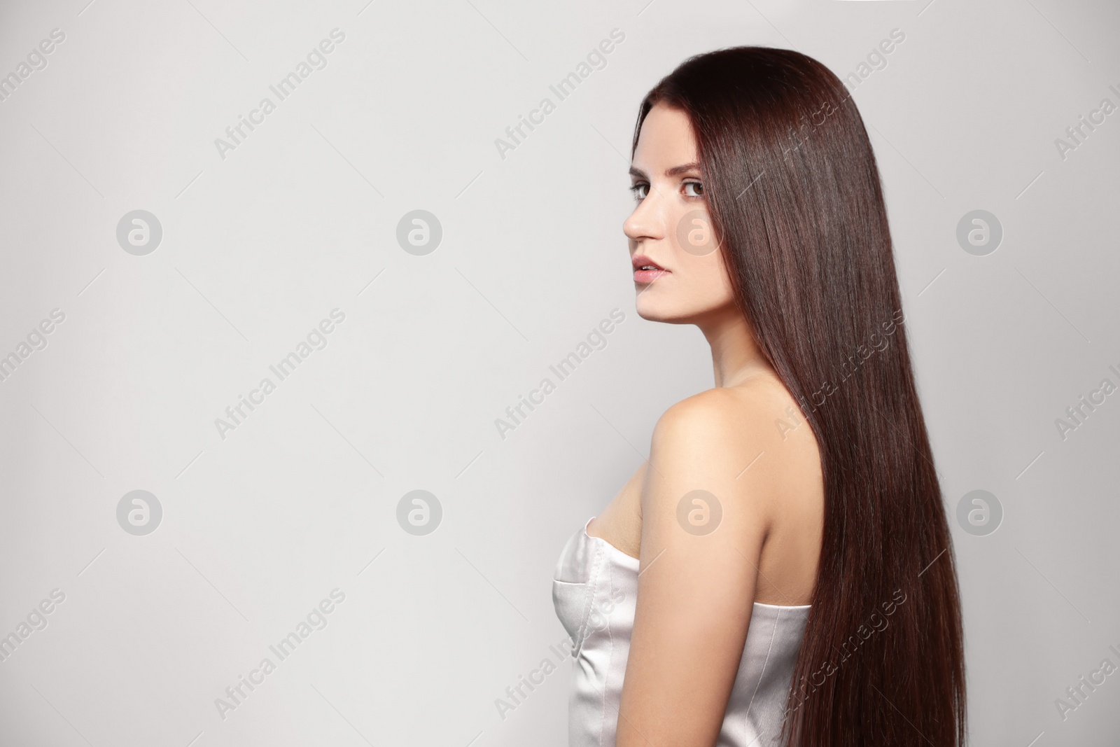 Photo of Portrait of beautiful young woman with healthy strong hair on light gray background, space for text