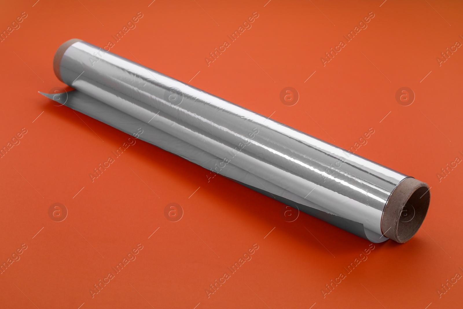 Photo of Roll of aluminum foil on orange background, closeup