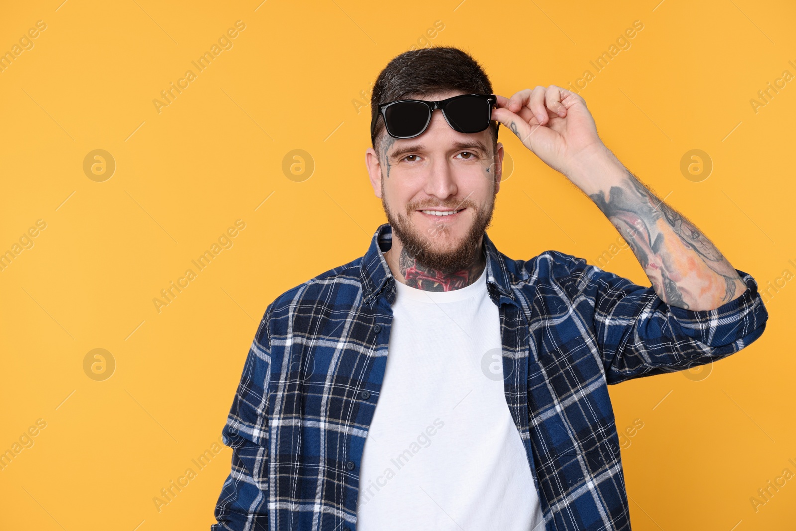 Photo of Portrait of handsome hipster man with stylish sunglasses on yellow background. Space for text