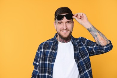 Photo of Portraithandsome hipster man with stylish sunglasses on yellow background. Space for text