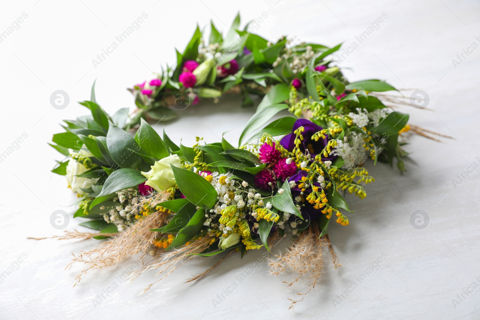 Photo of Beautiful wreath made of flowers and leaves on white table