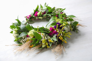 Beautiful wreath made of flowers and leaves on white table