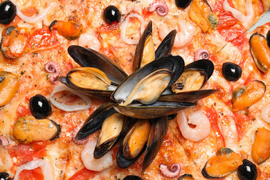 Tasty fresh pizza with seafood as background, closeup