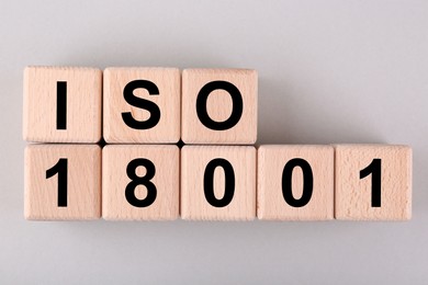Photo of International Organization for Standardization. Wooden cubes with abbreviation ISO and number 18001 on light grey background, flat lay