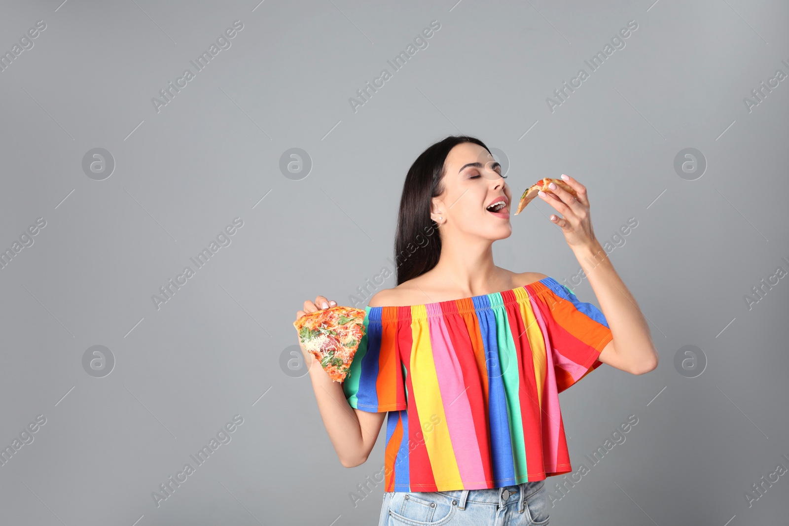 Photo of Beautiful woman with pizza on grey background, space for text