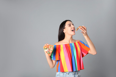 Beautiful woman with pizza on grey background, space for text