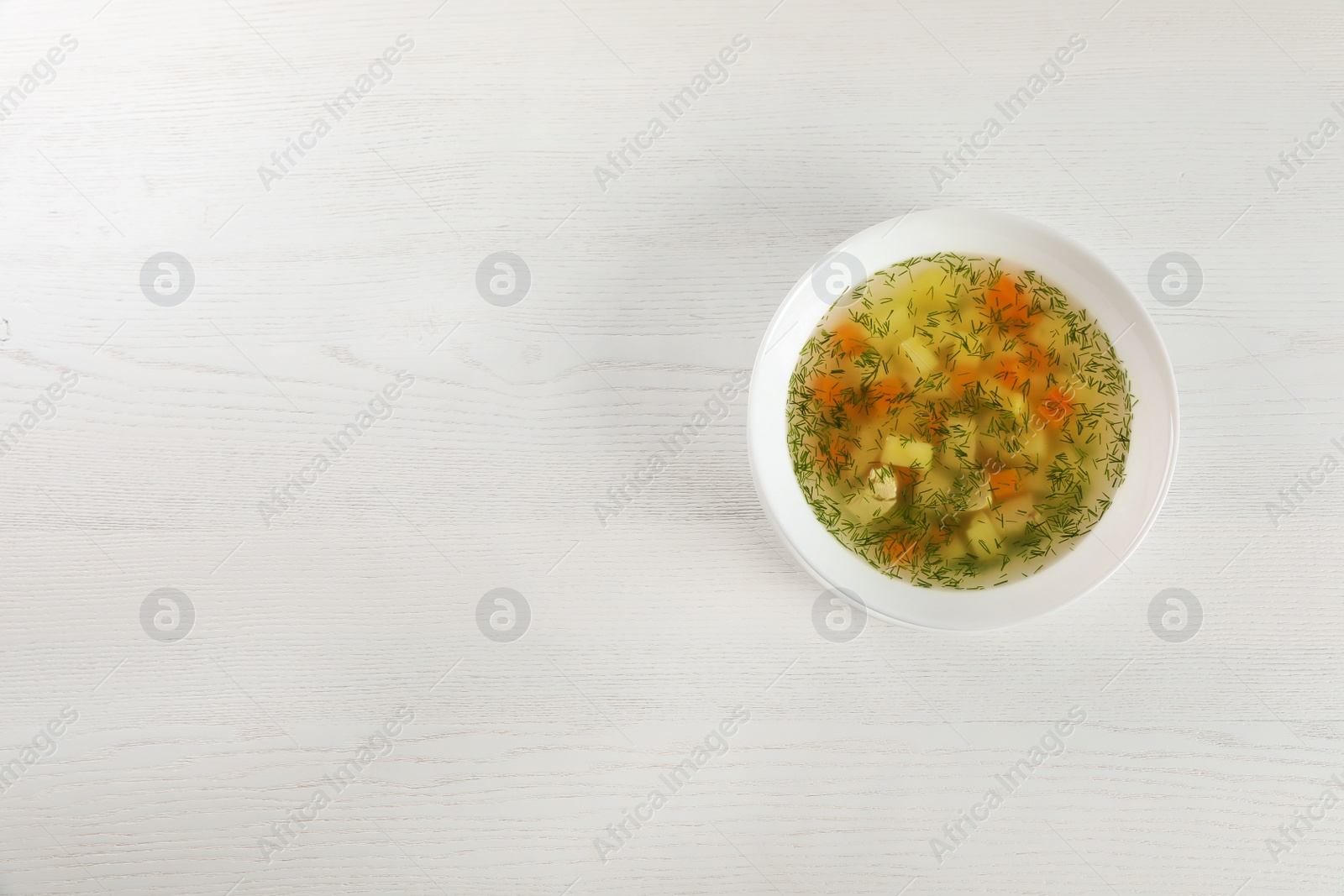 Photo of Bowl of fresh homemade soup to cure flu on wooden background, top view with space for text