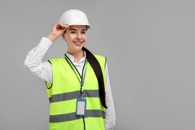 Photo of Engineer with hard hat and badge on grey background, space for text