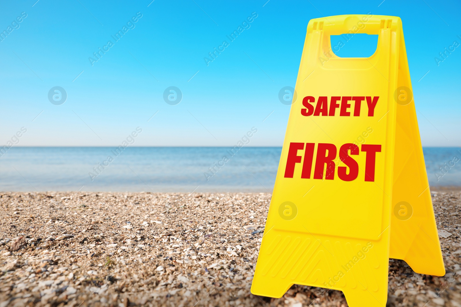 Image of Sign with phrase SAFETY FIRST on sandy beach, space for text 