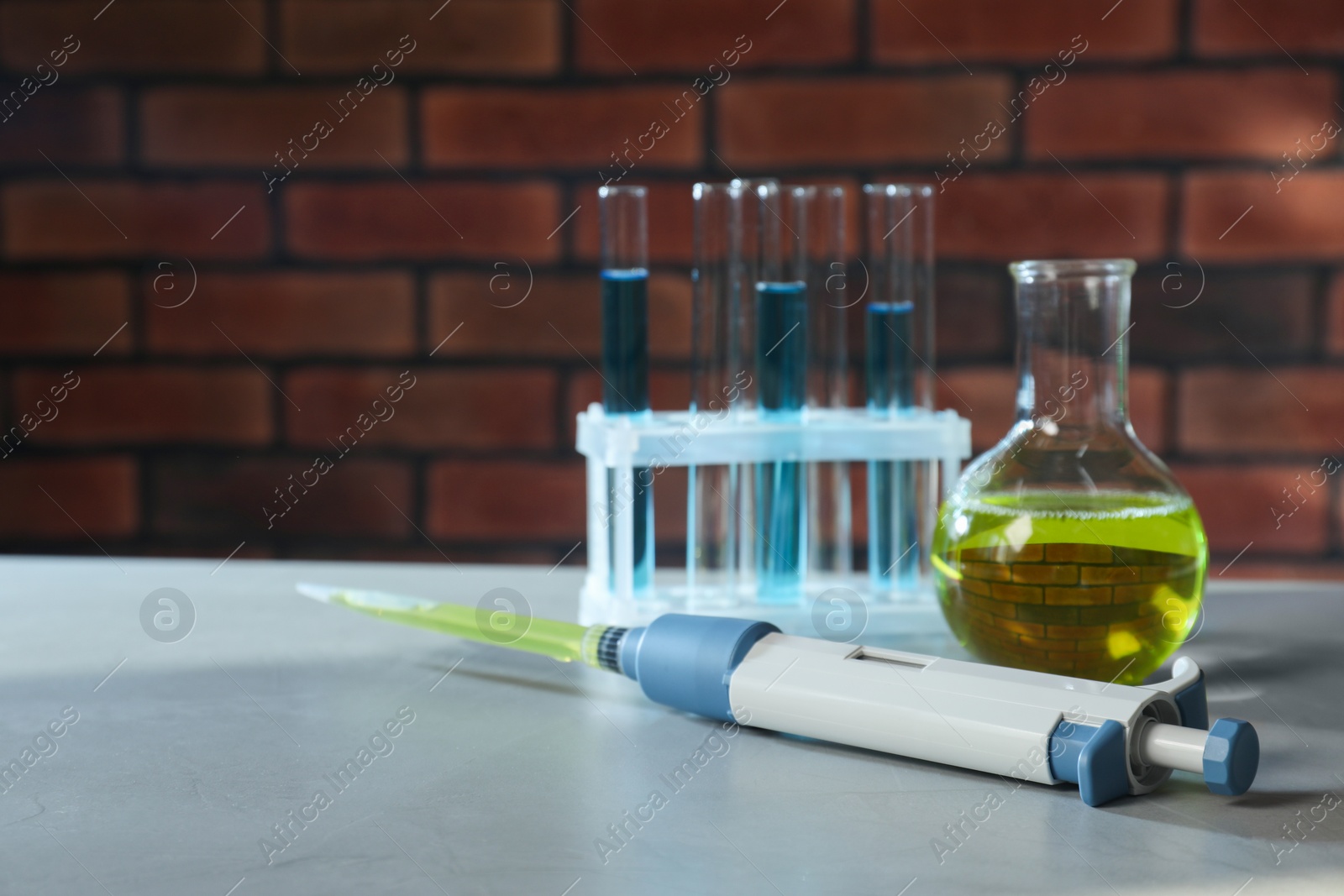 Photo of Laboratory analysis. Micropipette, flask and test tubes on grey table, space for text