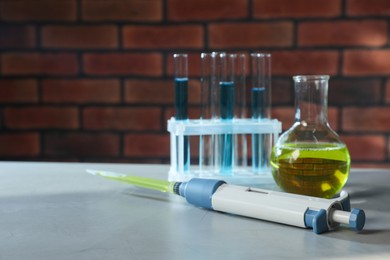 Laboratory analysis. Micropipette, flask and test tubes on grey table, space for text