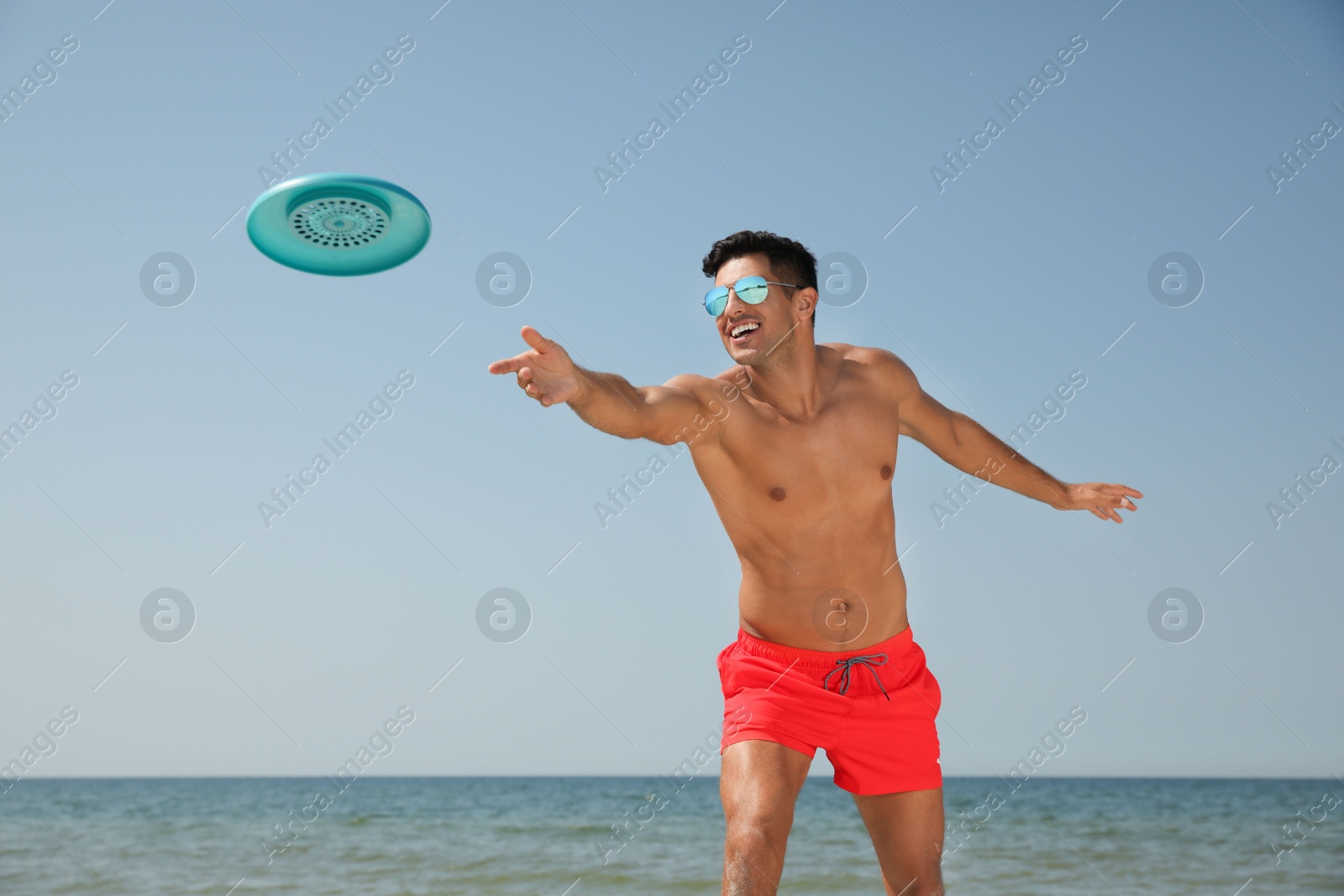 Photo of Happy man throwing flying disk at beach on sunny day