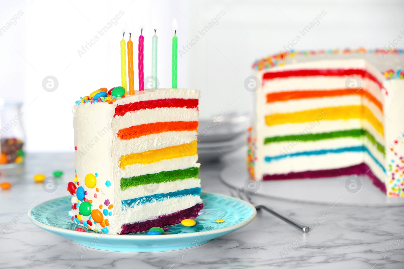 Photo of Delicious rainbow cake with candles for party on table