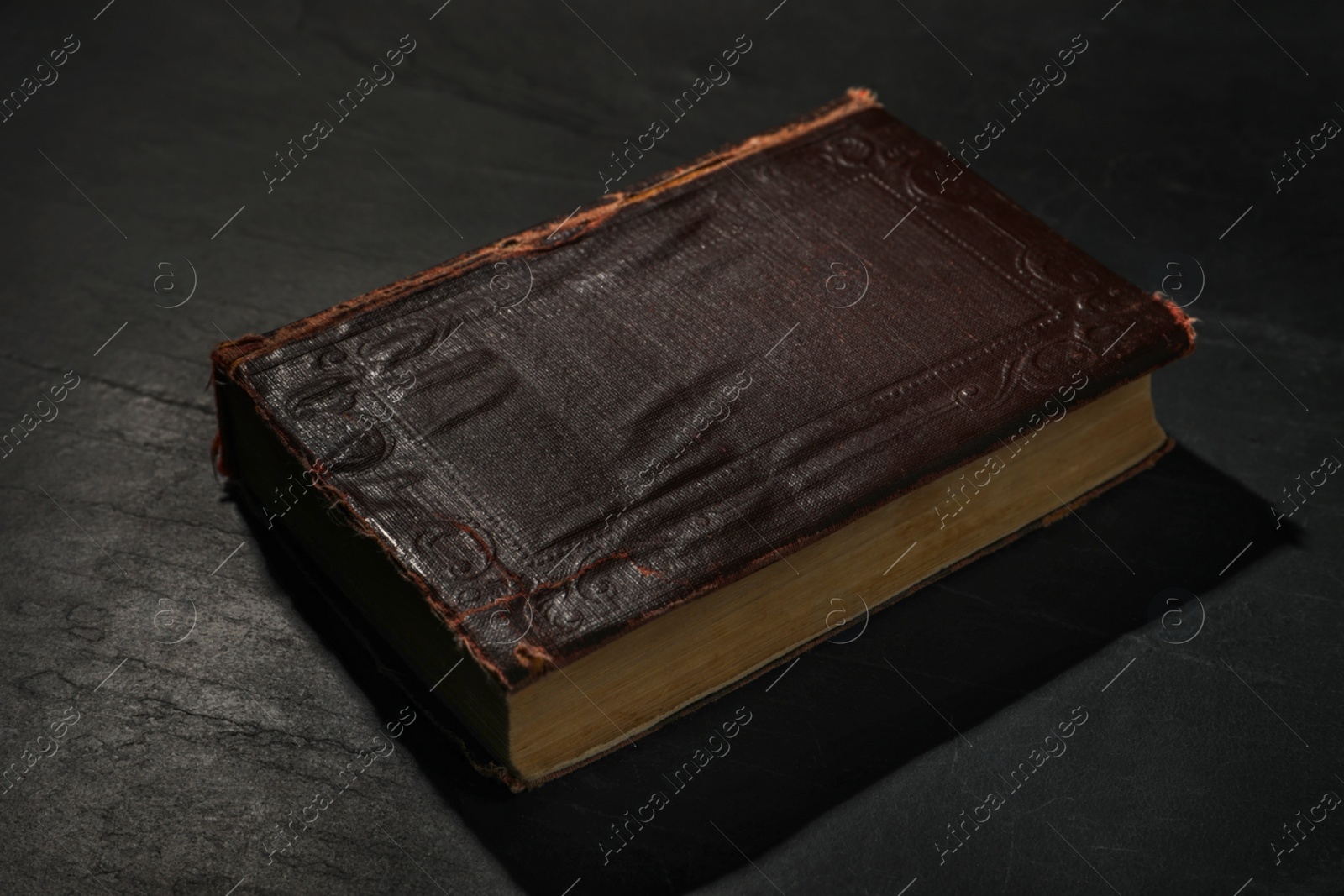 Photo of One old hardcover book on black textured table