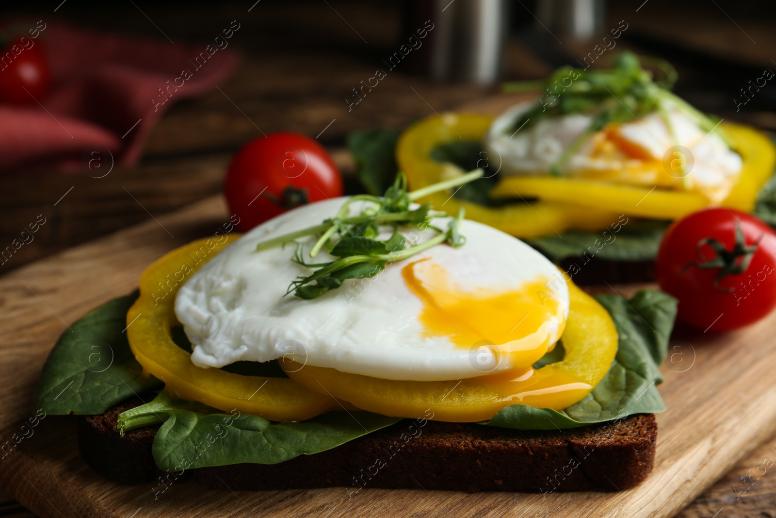 Photo of Delicious poached egg sandwich served on wooden board, closeup