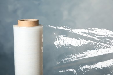 Photo of Roll of plastic stretch wrap film on blue background, closeup