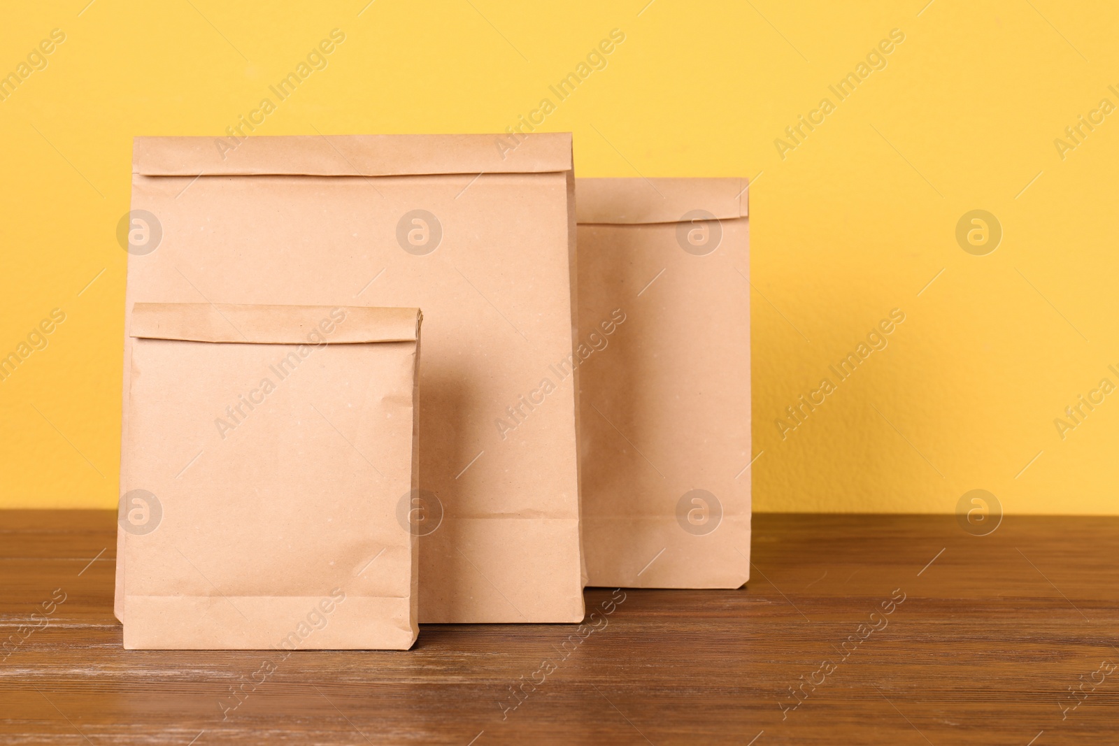 Photo of Paper bags on table against color background. Mockup for design